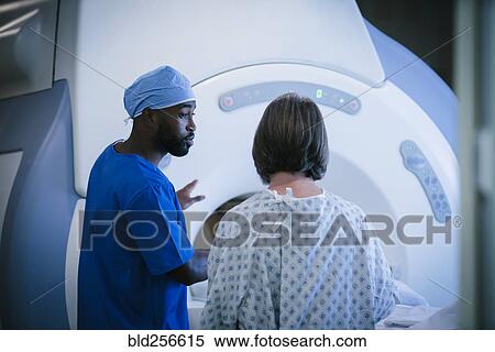 Stock Photography - Technician talking to patient at scanner. Fotosearch