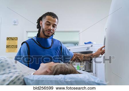 Stock Photo - Technician talking to patient near scanner. Fotosearch