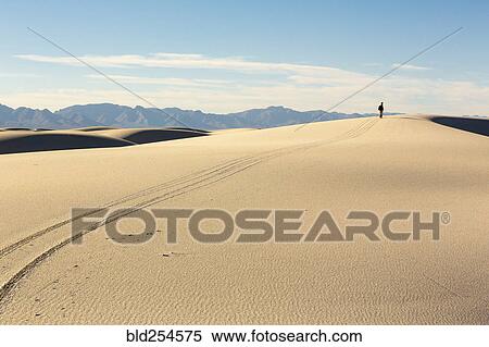 Trail leading to distant Caucasian man in desert View Large Photo Image Stock Photography - Trail leading to distant Caucasian man in desert. Fotosearch
