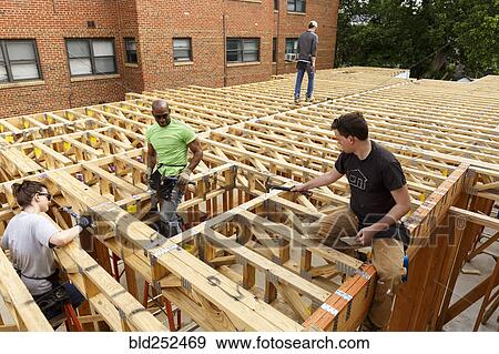 Volunteers hammering at construction site View Large Photo Image Stock Photo - Volunteers hammering at construction site. Fotosearch