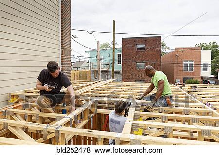 Volunteers hammering nails at construction site View Large Photo Image Stock Photo - Volunteers hammering nails at construction site. Fotosearch