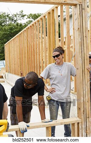 Volunteers holding frame at construction site View Large Photo Image Stock Image - Volunteers holding frame at construction site. Fotosearch