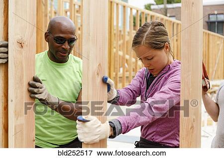 Stock Photo - Volunteers holding wall at construction site. Fotosearch