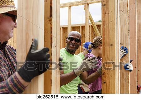 Stock Photo - Volunteers holding wall at construction site. Fotosearch