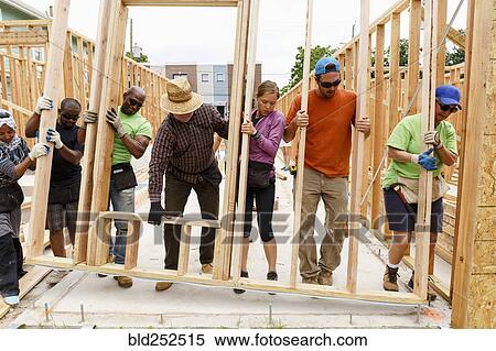 Volunteers lifting wall at construction site View Large Photo Image Stock Photography - Volunteers lifting wall at construction site. Fotosearch