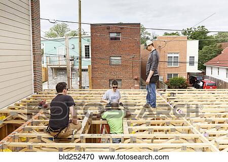 Stock Image - Volunteers on the roof at construction site. Fotosearch