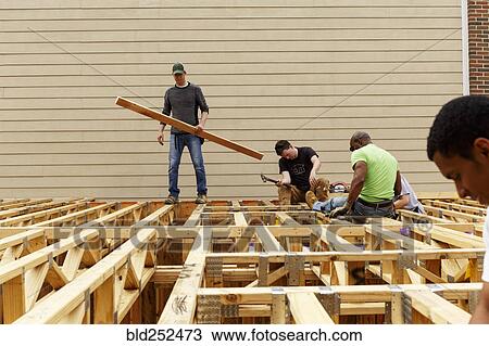Stock Image - Volunteers on the roof at construction site. Fotosearch