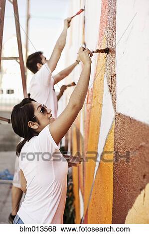 Stock Photo - Volunteers painting wall. Fotosearch