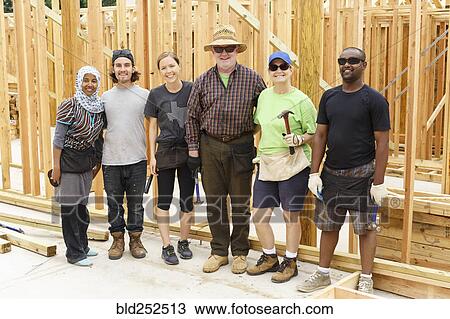 Stock Image - Volunteers posing at construction site. Fotosearch