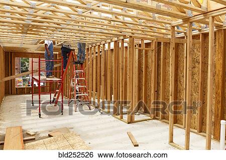 Stock Photograph - Volunteers standing on ladders and scaffolding at construction site. Fotosearch