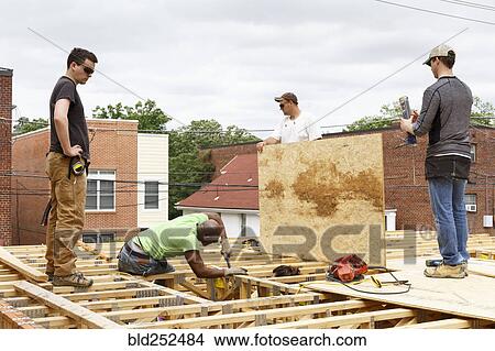 Volunteers working on the roof at construction site View Large Photo Image Picture - Volunteers working on the roof at construction site. Fotosearch