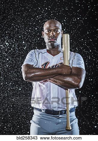Stock Image - Water splashing on Black baseball player holding bat. Fotosearch