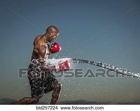 Picture - Water splashing on black boxer punching. Fotosearch