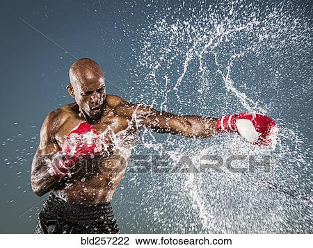 Stock Image - Water splashing on black boxer punching. Fotosearch