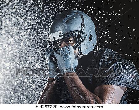 Stock Photo - Water splashing on black football player. Fotosearch