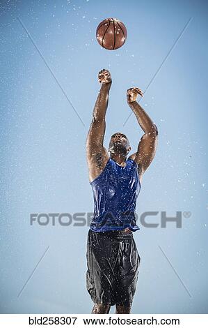 Stock Photo - Water splashing on Black man shooting basketball. Fotosearch