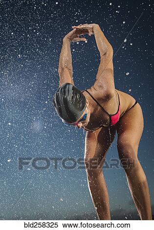 Stock Photography - Water splashing on Caucasian swimmer stretching arms. Fotosearch