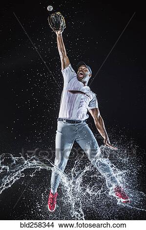 Picture - Water splashing on legs Black baseball player catching baseball. Fotosearch