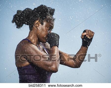 Stock Image - Water splashing on sparring Black woman. Fotosearch