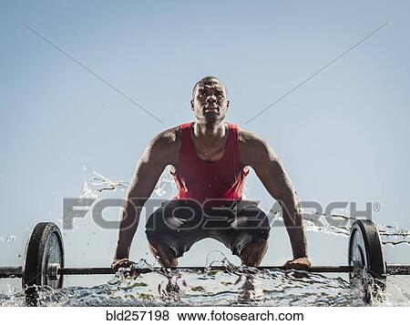 Water spraying on black man preparing for lifting barbell View Large Photo Image Stock Photo - Water spraying on black man preparing for lifting barbell. Fotosearch
