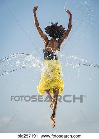 Stock Image - Water spraying on black woman ballet dancing. Fotosearch