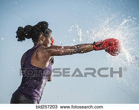 Stock Image - Water spraying on black woman boxing. Fotosearch