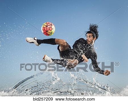 Water spraying on Hispanic man kicking soccer ball View Large Photo Image Stock Photo - Water spraying on Hispanic man kicking soccer ball. Fotosearch