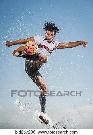 Water spraying on Hispanic man kicking soccer ball View Large Photo Image Stock Photograph - Water spraying on Hispanic man kicking soccer ball. Fotosearch