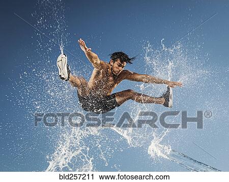 Water spraying on jumping Hispanic man View Large Photo Image Stock Image - Water spraying on jumping Hispanic man. Fotosearch