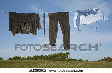 Stock Image - Wet business suit hanging on clothesline in field. Fotosearch
