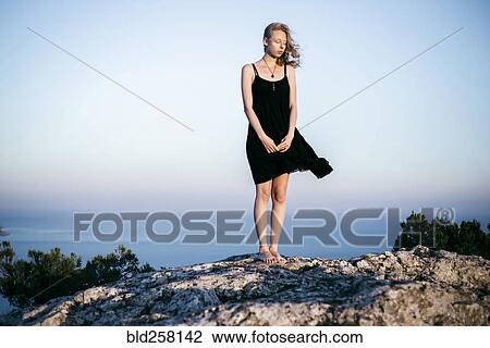 Wind blowing dress of Caucasian woman standing on rock near ocean View Large Photo Image Stock Image - Wind blowing dress of Caucasian woman standing on rock near ocean. Fotosearch