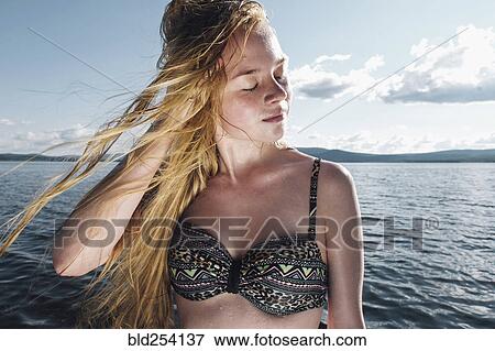 Stock Photo - Wind blowing hair of Caucasian teenage girl in ocean. Fotosearch