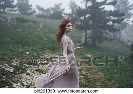 Stock Image - Wind blowing hair of Caucasian woman in field. Fotosearch