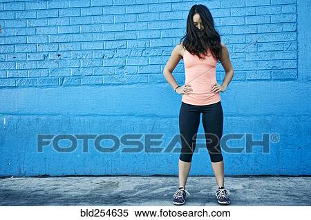 Stock Photography - Wind blowing hair of mixed race woman at blue wall. Fotosearch