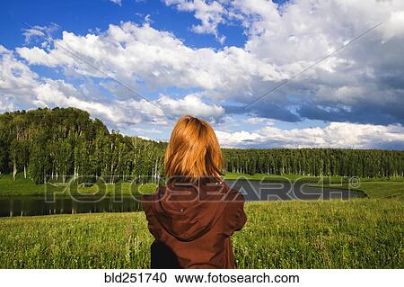 Stock Image - Woman admiring scenic view of river. Fotosearch