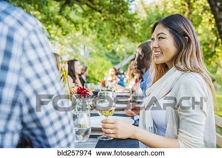 Picture - Woman enjoying wine at party outdoors. Fotosearch