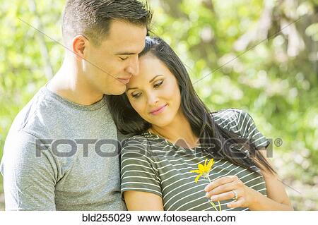 Stock Photo - Woman holding flower leaning on man. Fotosearch