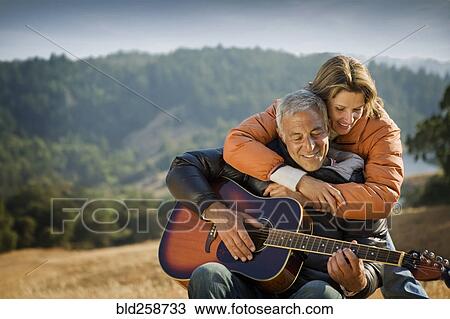 Stock Image - Woman hugging man playing guitar. Fotosearch