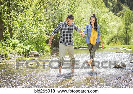 Stock Photo - Woman kicking water on man in river. Fotosearch