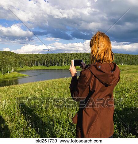 Woman photographing river with cell phone View Large Photo Image Stock Photo - Woman photographing river with cell phone. Fotosearch