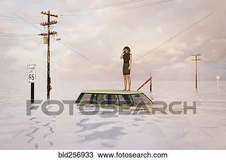Stock Image - Woman standing on roof of car in flood. Fotosearch