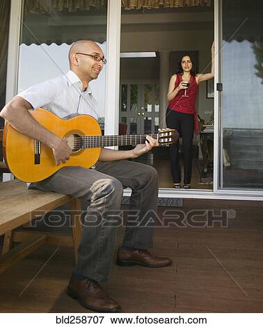Woman watching man sitting on bench playing guitar View Large Photo Image Stock Photo - Woman watching man sitting on bench playing guitar. Fotosearch
