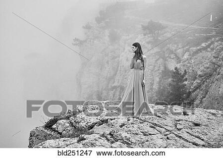 Woman wearing dress standing on rock in fog View Large Photo Image Stock Photo - Woman wearing dress standing on rock in fog. Fotosearch