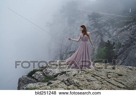 Woman wearing dress standing on rock in fog View Large Photo Image Stock Photo - Woman wearing dress standing on rock in fog. Fotosearch