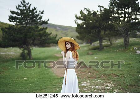 Stock Photography - Woman wearing sun hat standing in field. Fotosearch