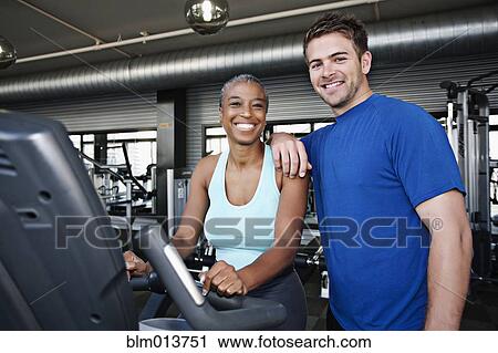 Stock Image - Woman with personal trainer in health club. Fotosearch