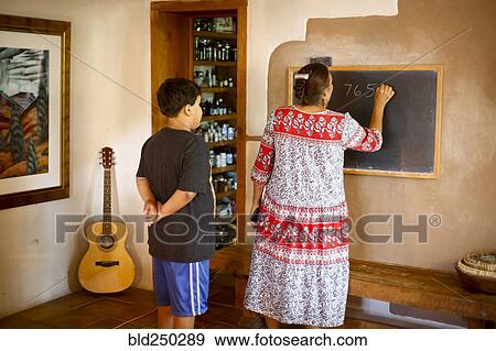 Stock Photo - Woman writing equation on blackboard for son. Fotosearch