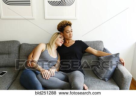 Women cuddling on sofa View Large Photo Image Stock Photo - Women cuddling on sofa. Fotosearch