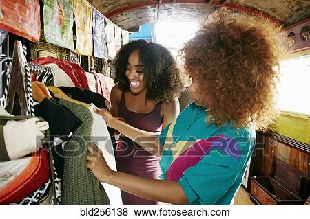 Women examining clothing in retail store on bus View Large Photo Image Stock Photo - Women examining clothing in retail store on bus. Fotosearch