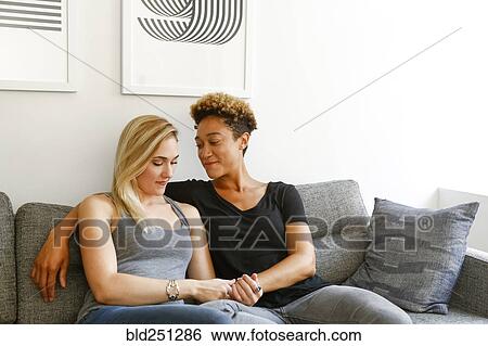 Women holding hands on sofa View Large Photo Image Stock Photograph - Women holding hands on sofa. Fotosearch